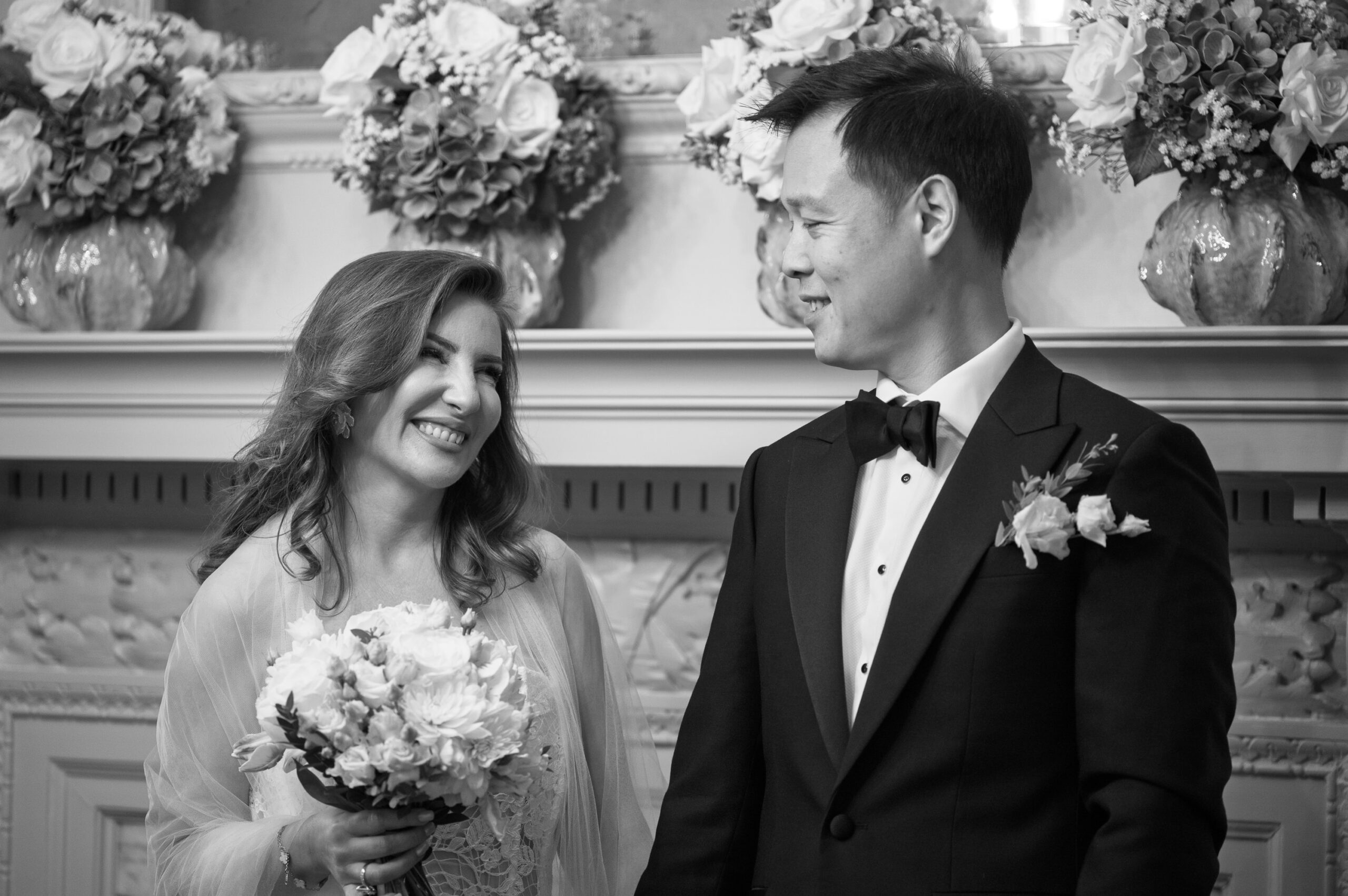 Black and white photo of Nicoleta smiling at Alistair during their Old Marylebone Town Hall ceremony