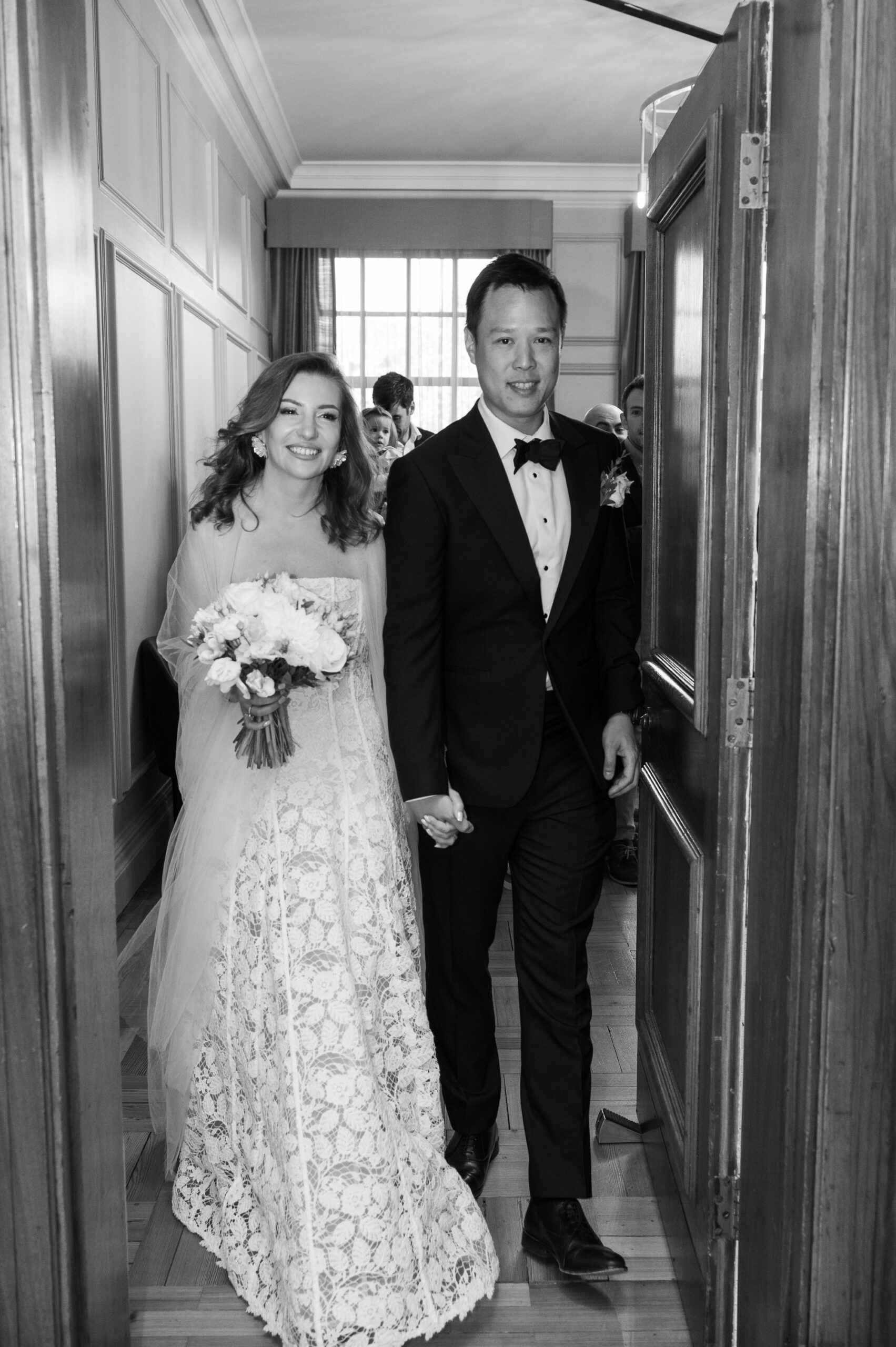 Black and white photo of the newlyweds walking out through the doors of the Pimlico Room at Old Marylebone Town Hall