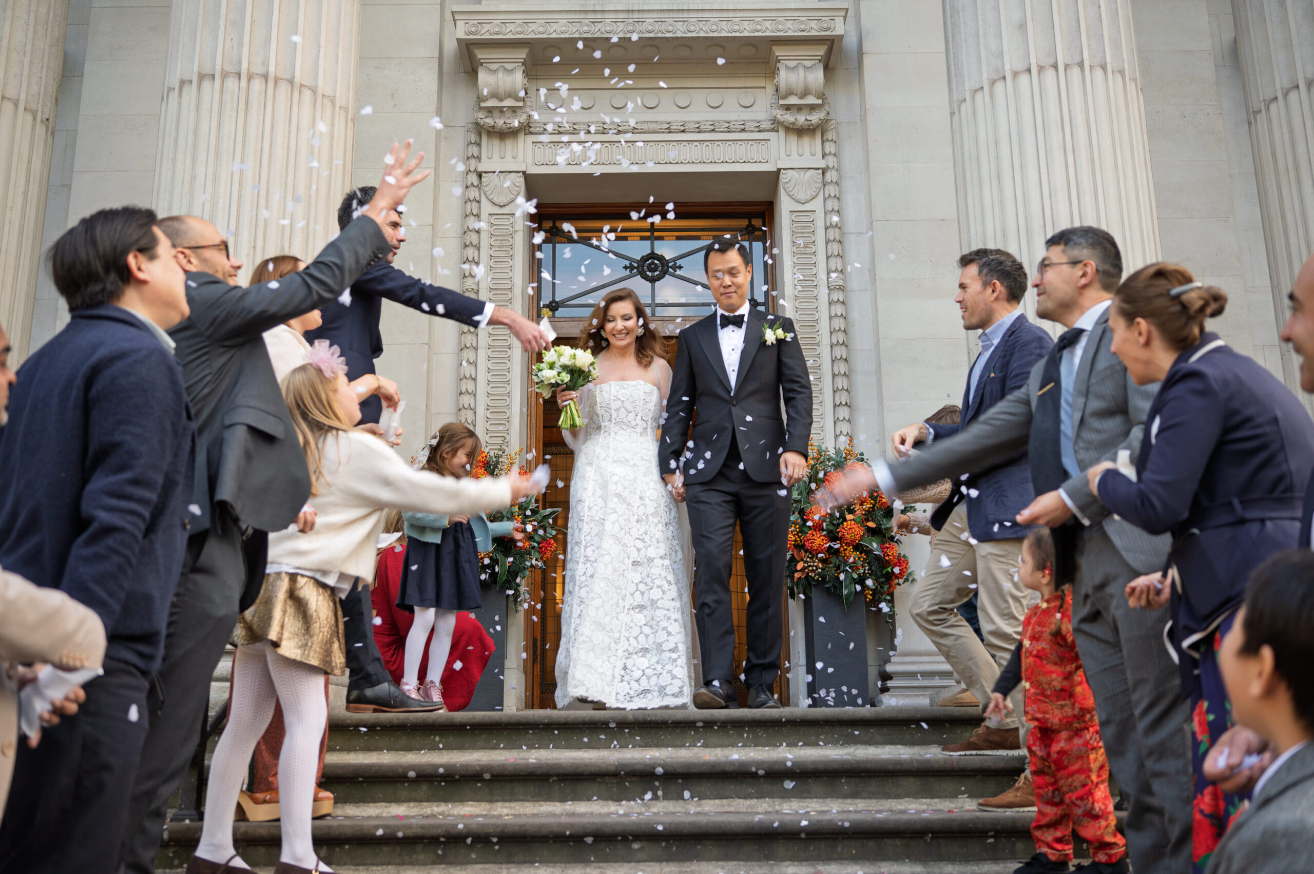 Family and friends throwing confetti over Nicoleta and Alistair on the front steps of Old Marylebone Town Hall