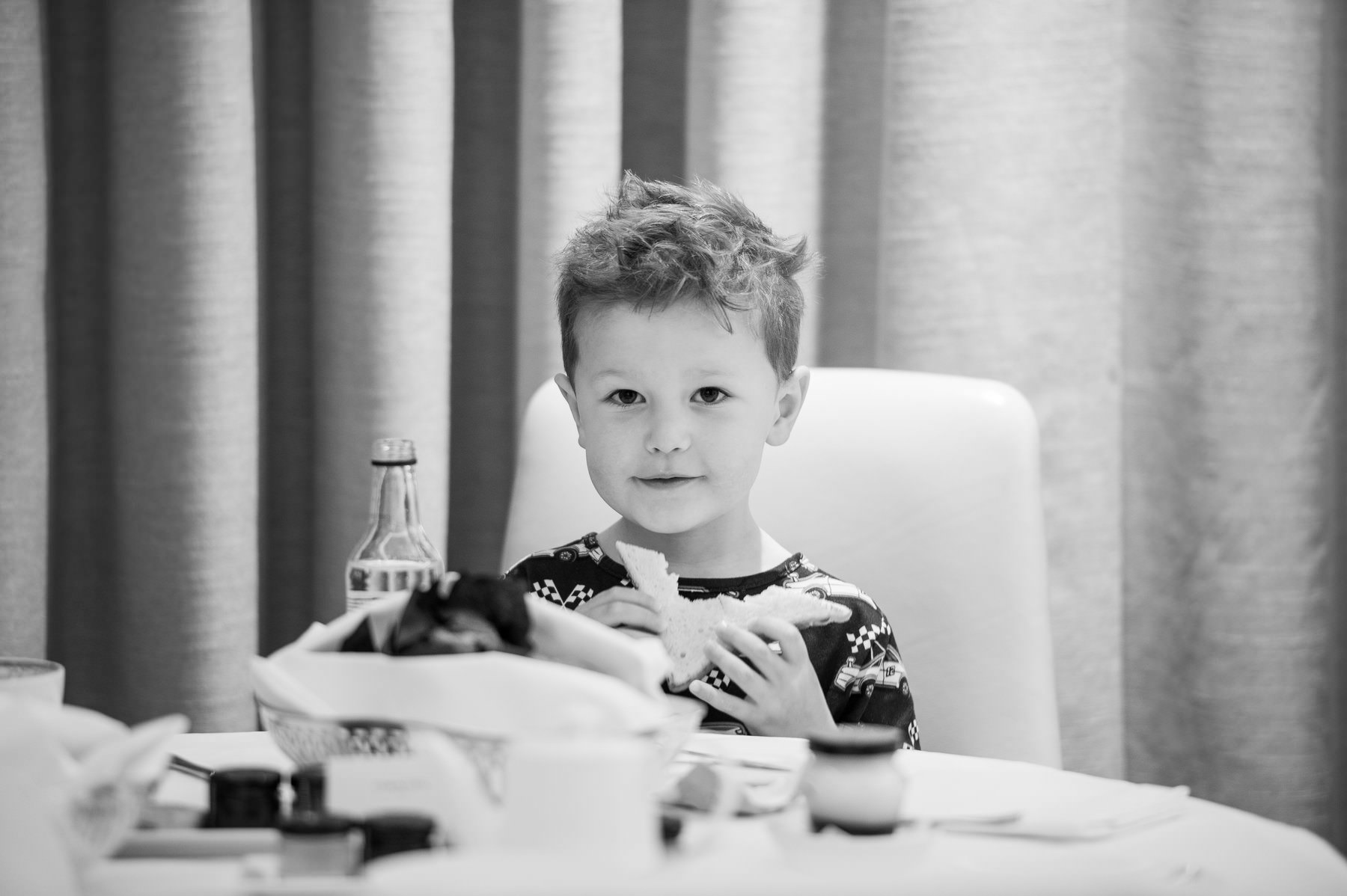 Black and white photo of the couple's young son at the breakfast table in the Corinthia hotel room on the wedding morning