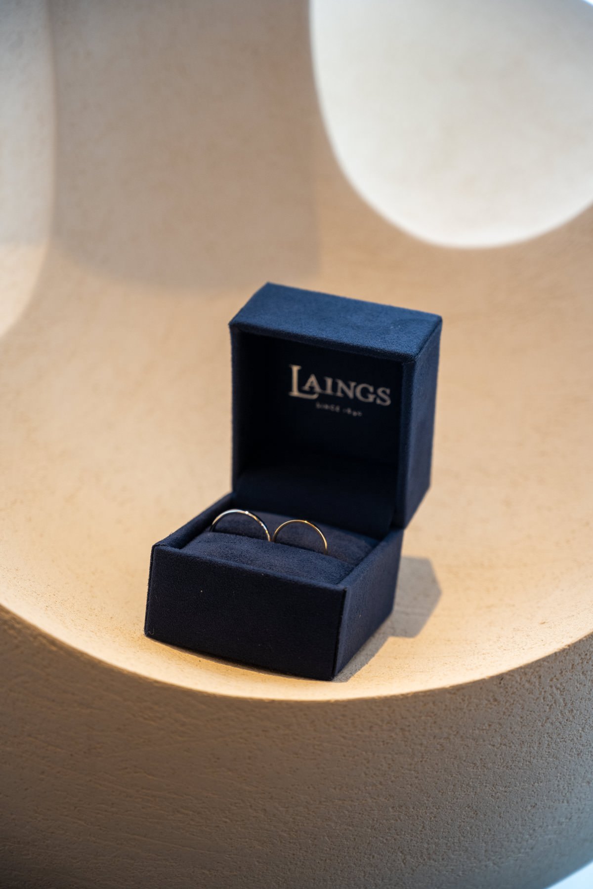 Two wedding rings in a navy ring box, lit from behind